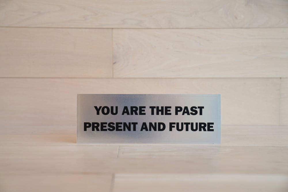 A sticker with a shiny silver surface reading YOU ARE THE PAST PRESENT AND FUTURE