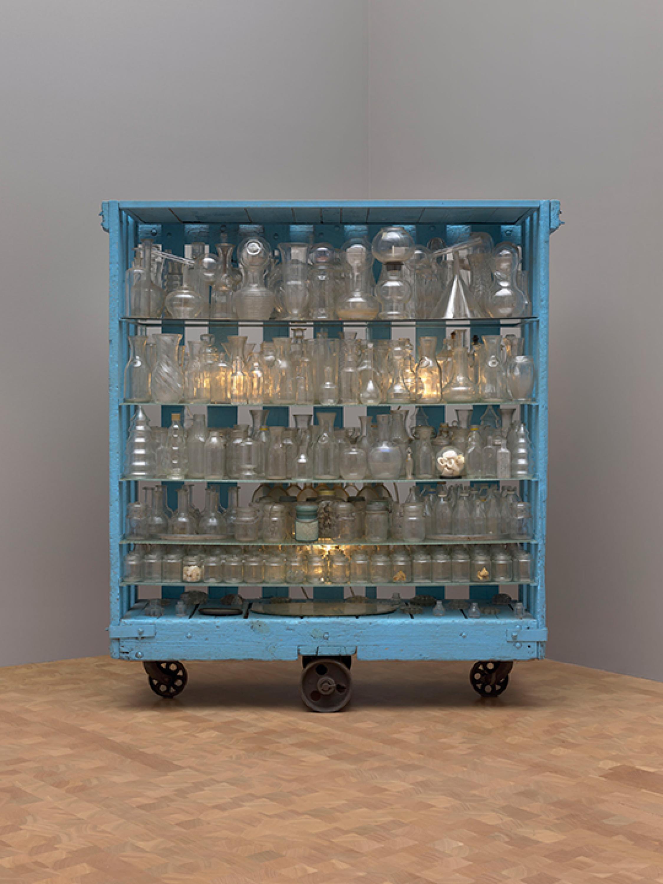 Gran caja azul de tres ruedas con recipientes de vidrio y estanterías de vidrio en el interior.