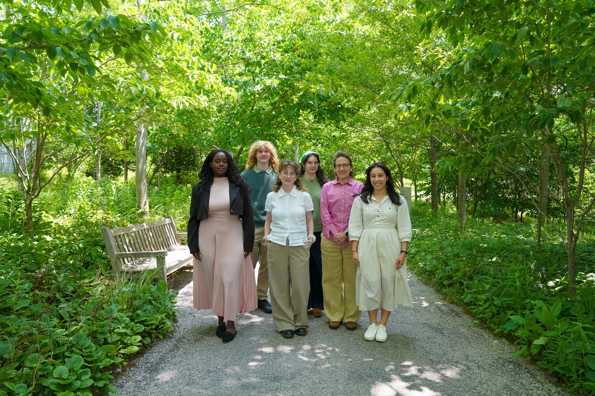 A group of people standing on a path in a wooded area