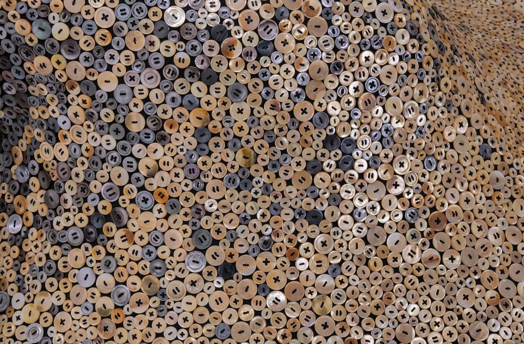 A great number of buttons are sewn to a mysterioud form.