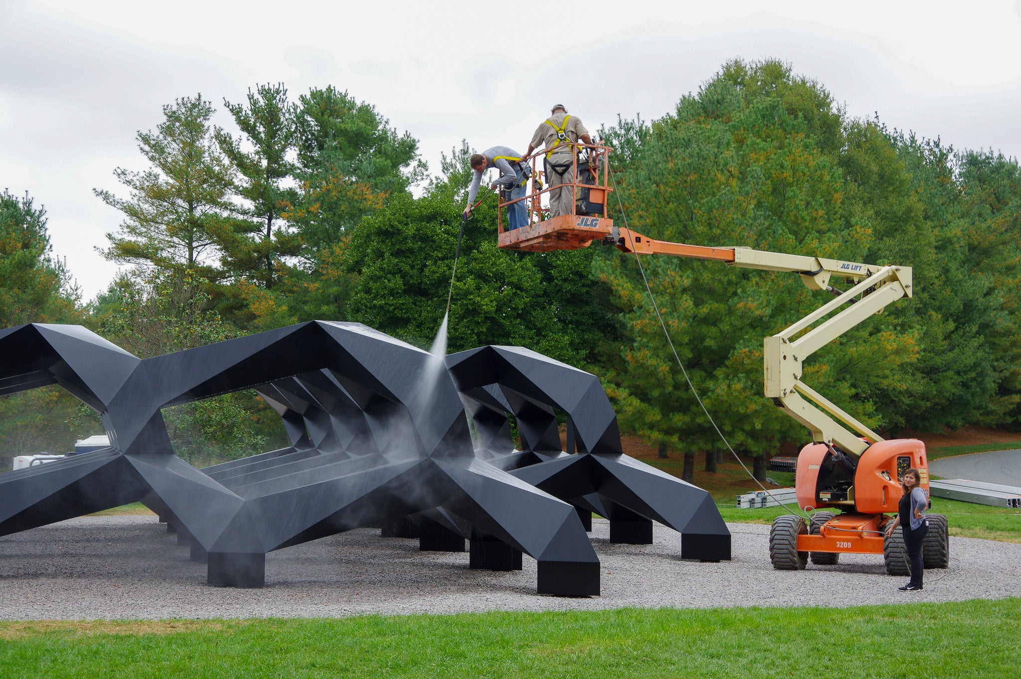 Una gran escultura geométrica negra es lavada desde arriba.