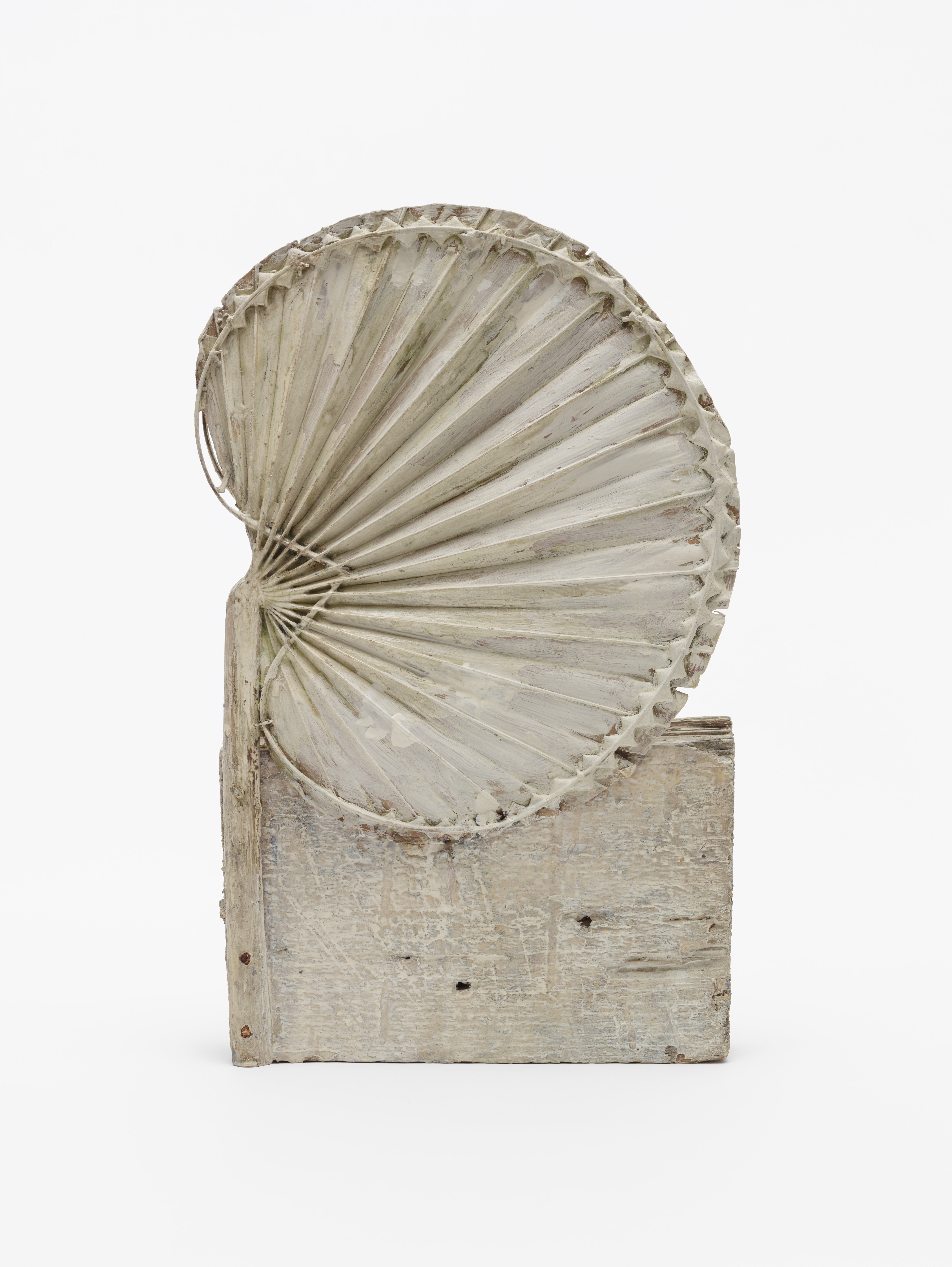 A dirtied white sculpture with a fan-like structure attached to a rectangular base