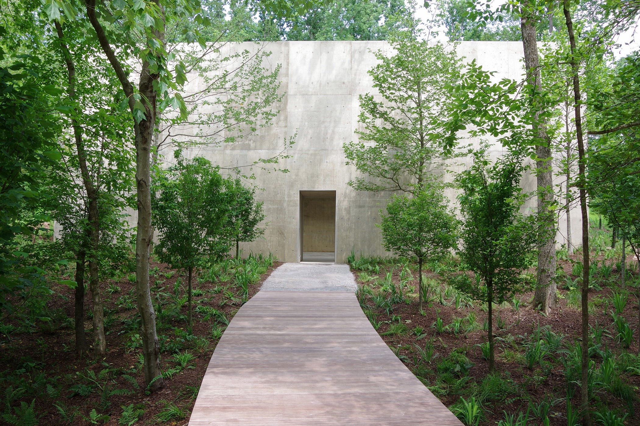 Blocky concrete building in the woods with pathway leading to entrance