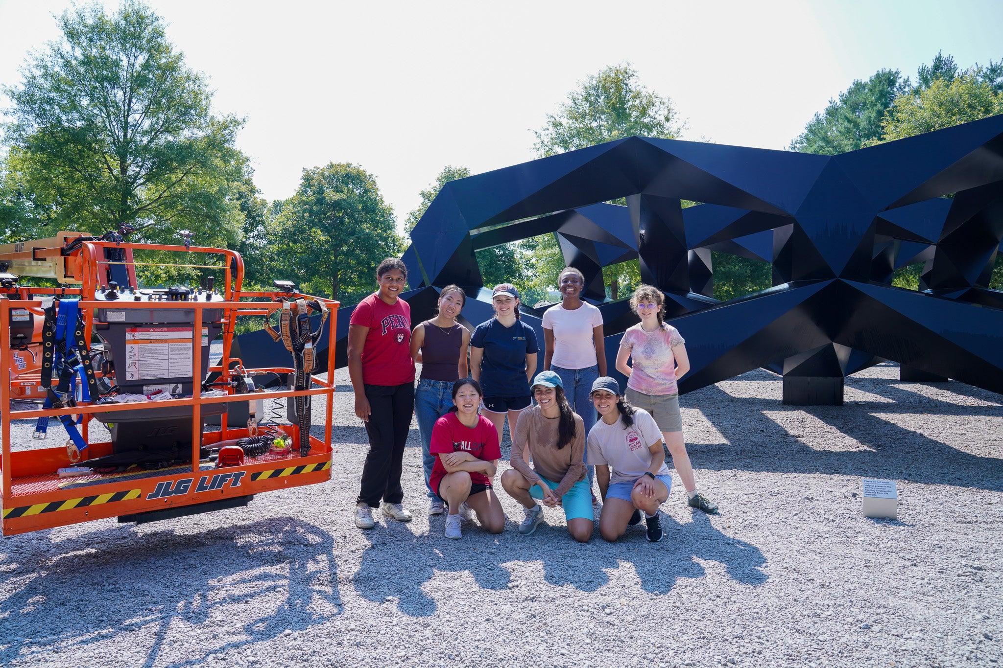 A group of students stands in front of a sculptuere
