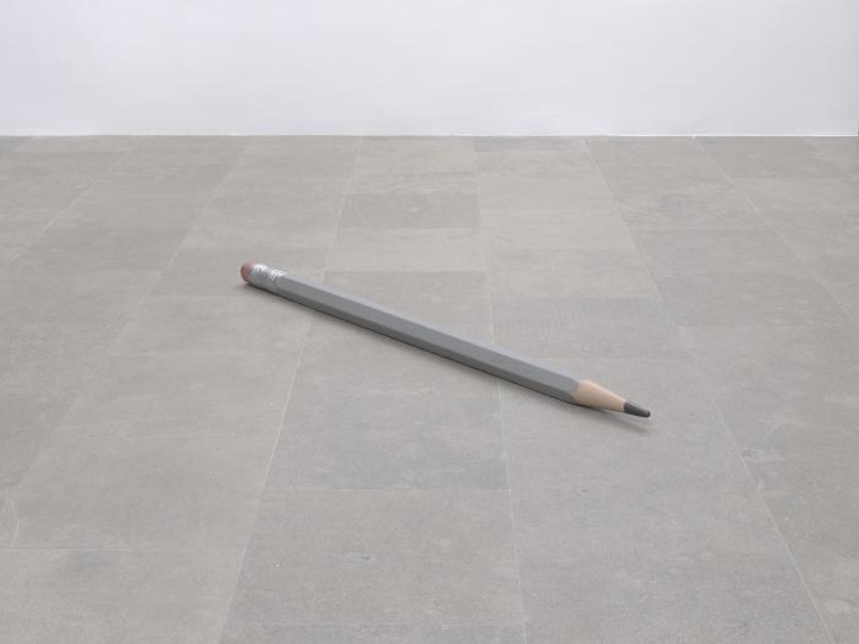 Un gran lápiz gris afilado sobre un suelo de hormigón.