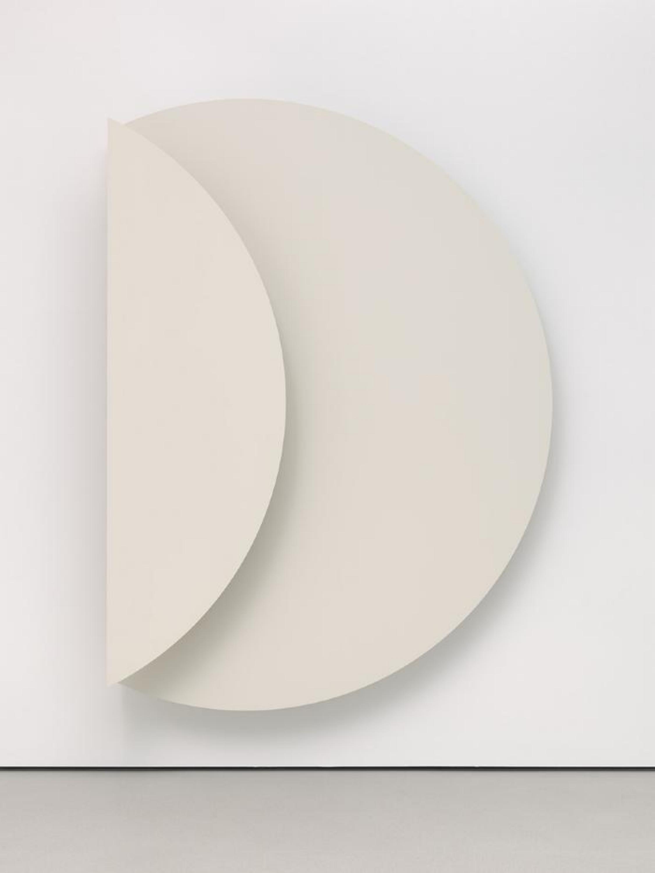 Un círculo blanco se encuentra sobre una pared blanca, con un panel a su izquierda que parece estar plegado.