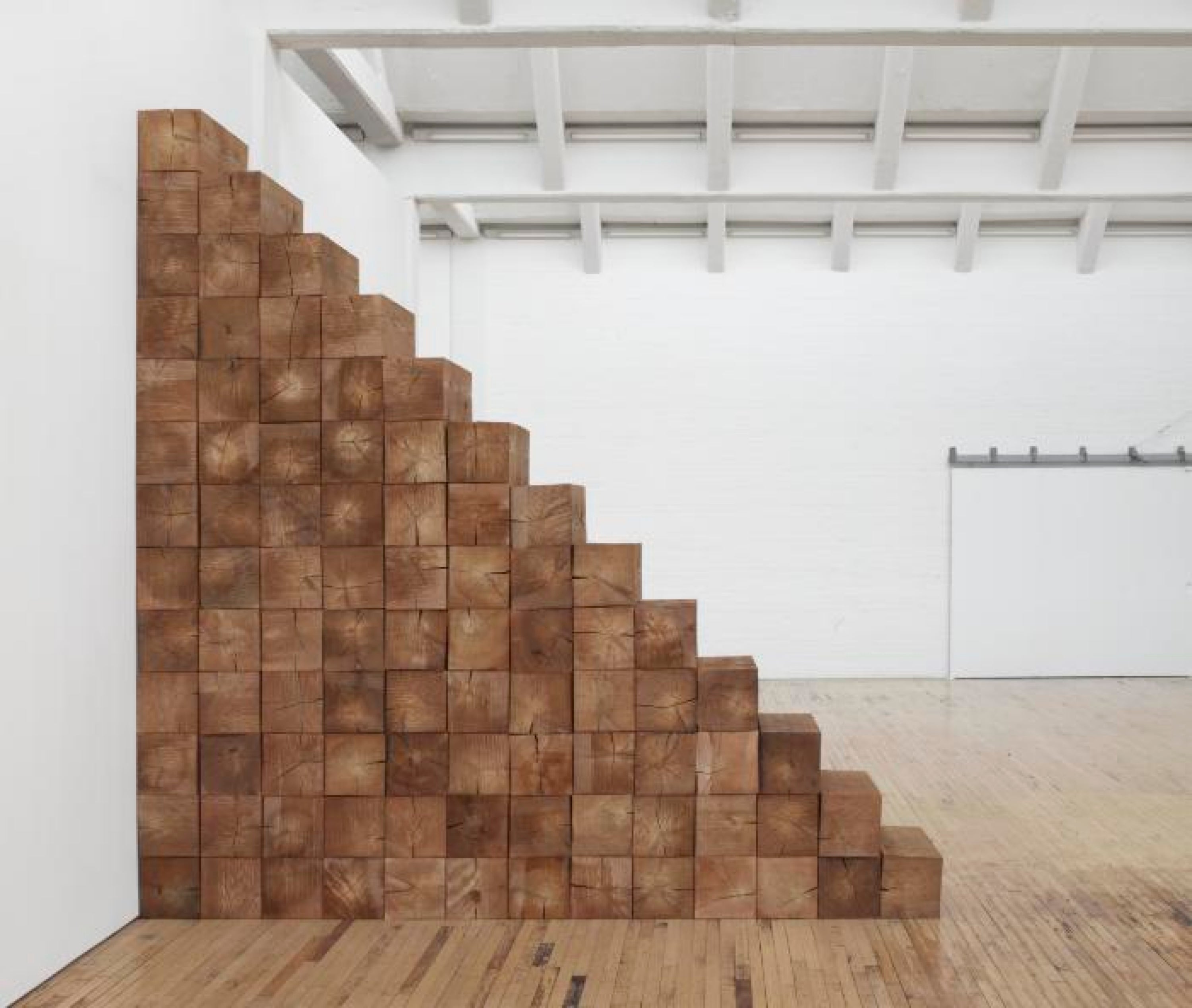 Bloques de madera apilados formando una escalera que llega hasta el techo.