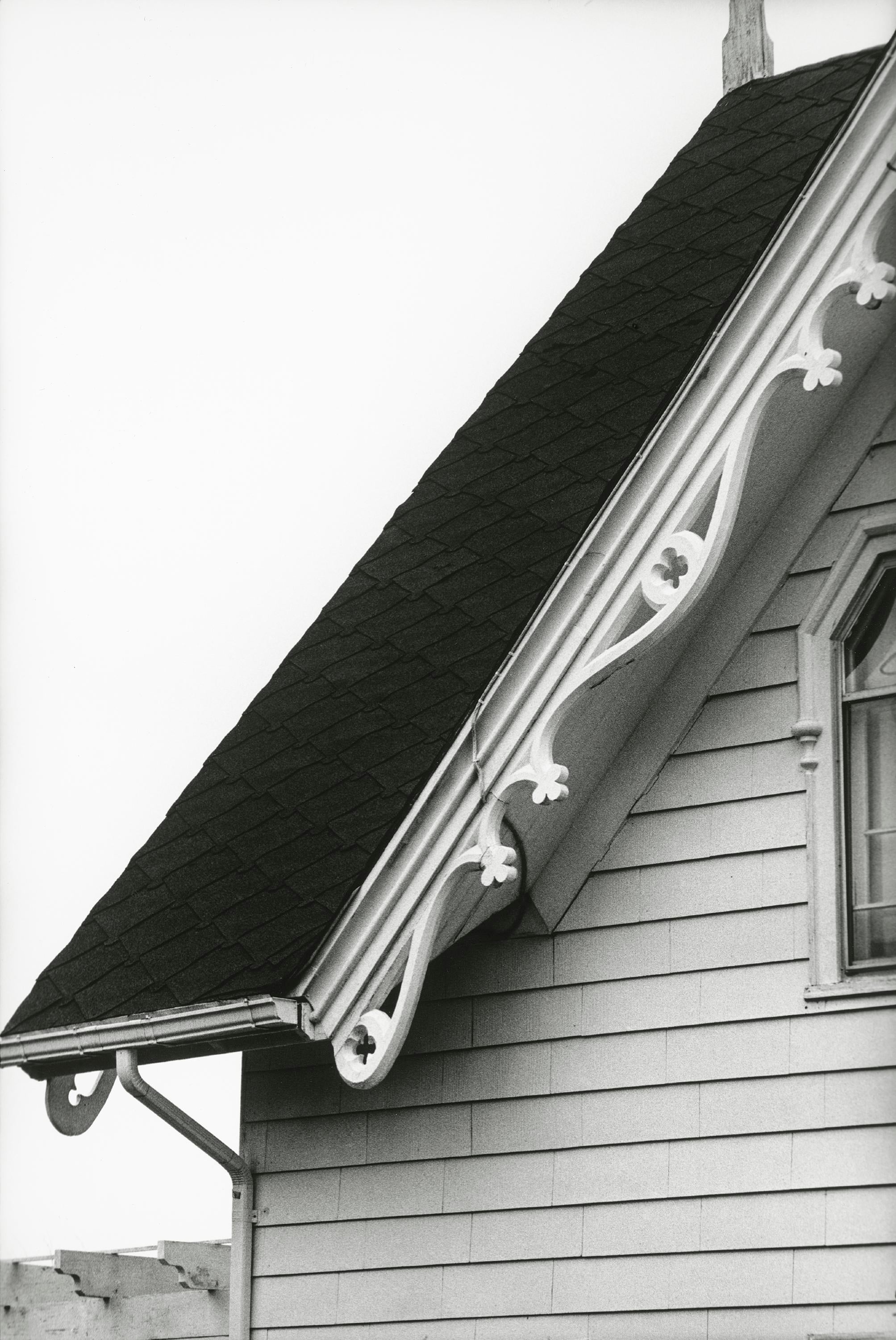 Fotografía en blanco y negro de un tejado a dos aguas y una tira de tejas negras.