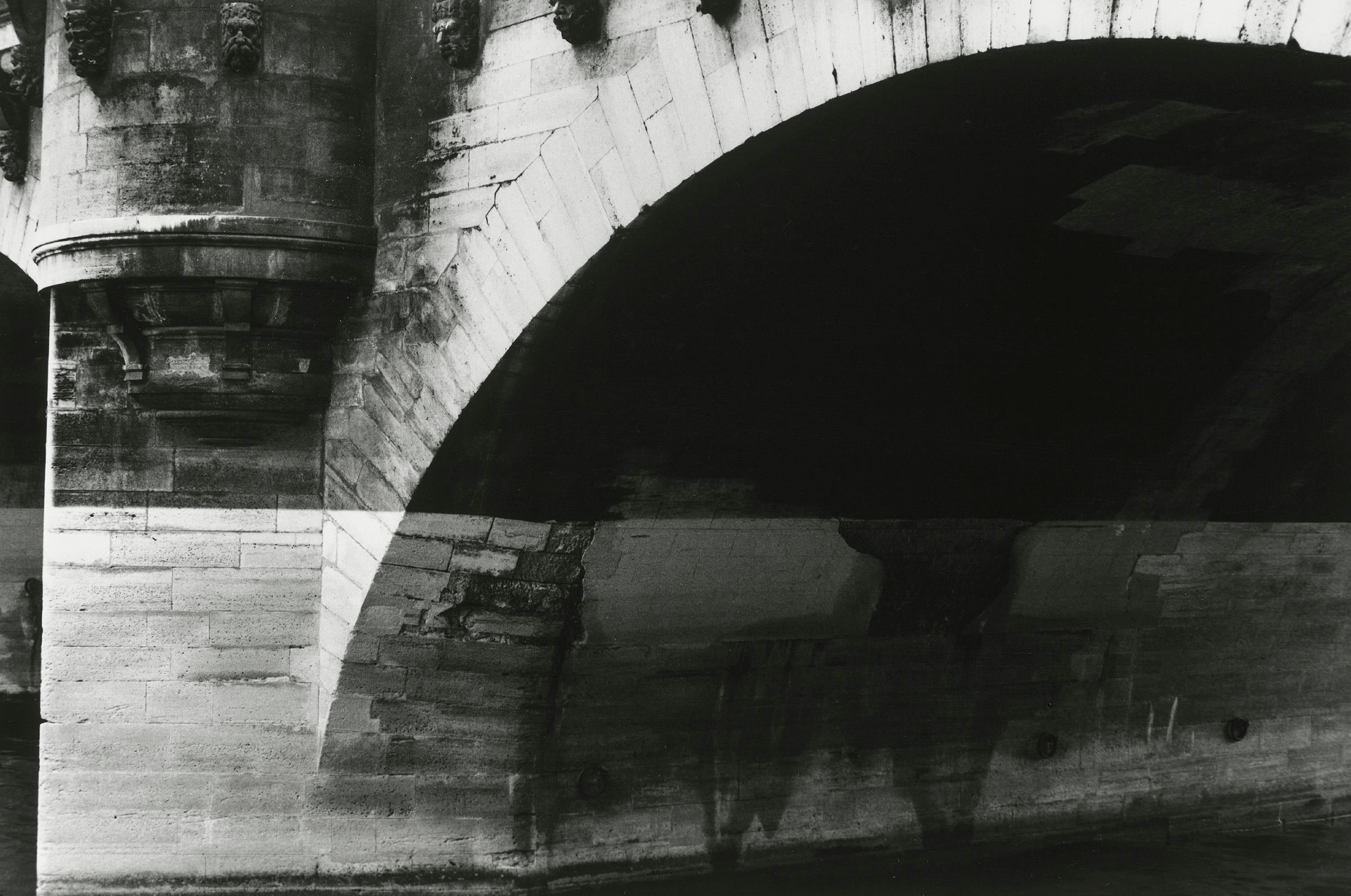 Un arco de puente parcialmente cubierto de sombras.