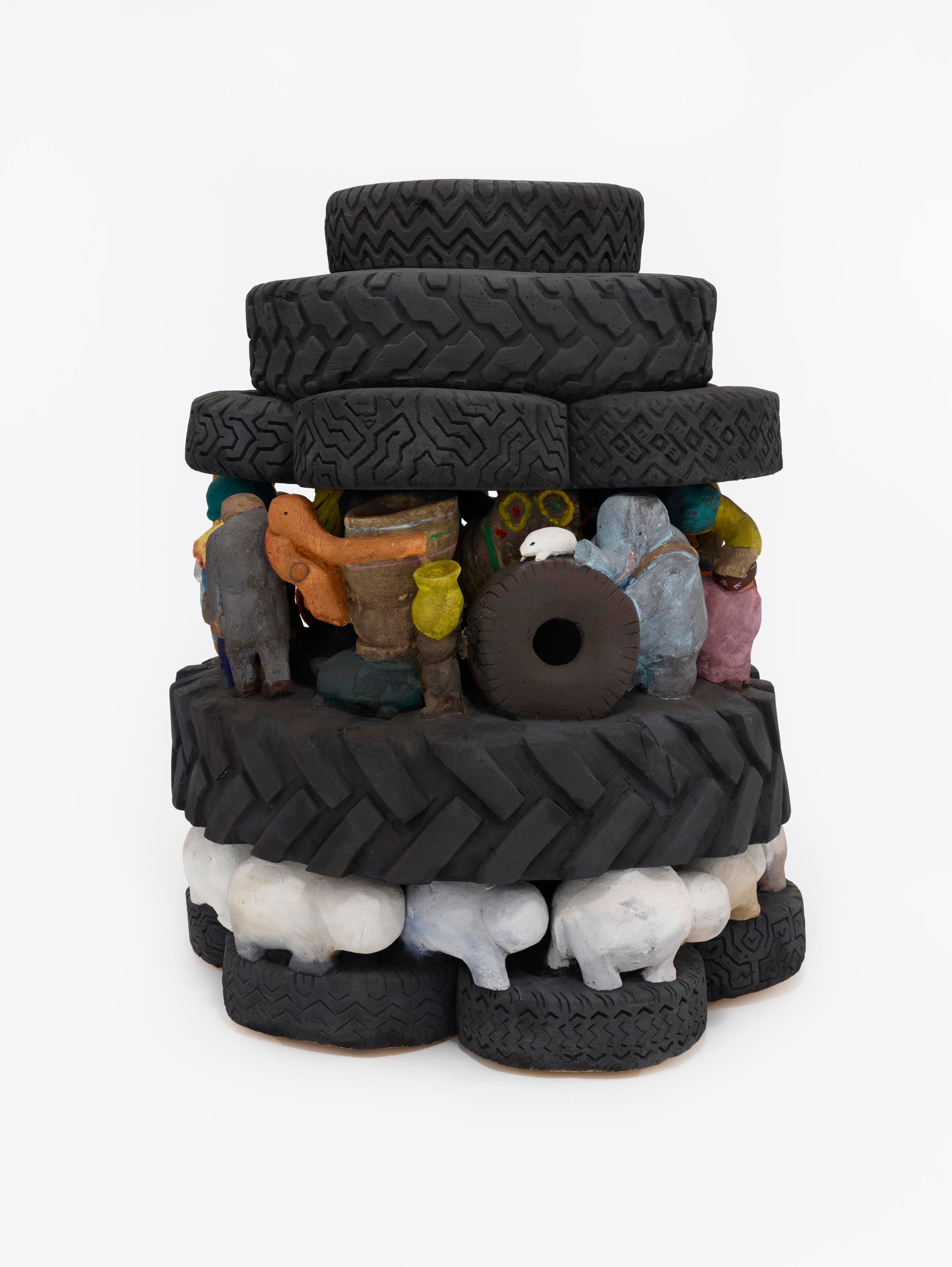 Five stacked layers of toy vehicle tires sit vertically. Between two of the layers are abstract white, toy sheep figures. Between two other layers are abstract toy animal and people figures.