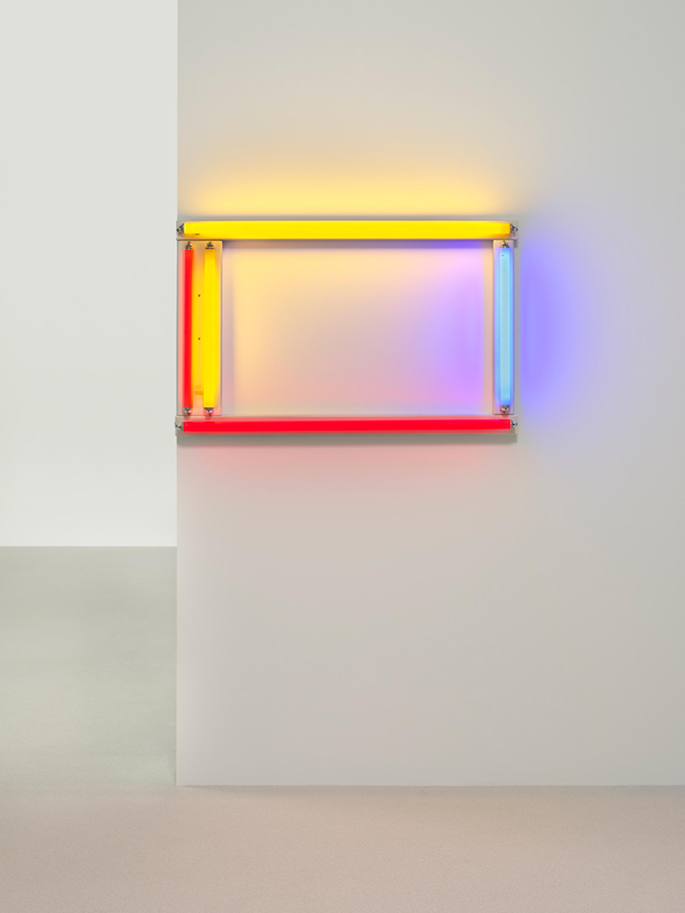 An installation of two red, two yellow and one blue florescent light forming a rectangle is mounted on to a white wall