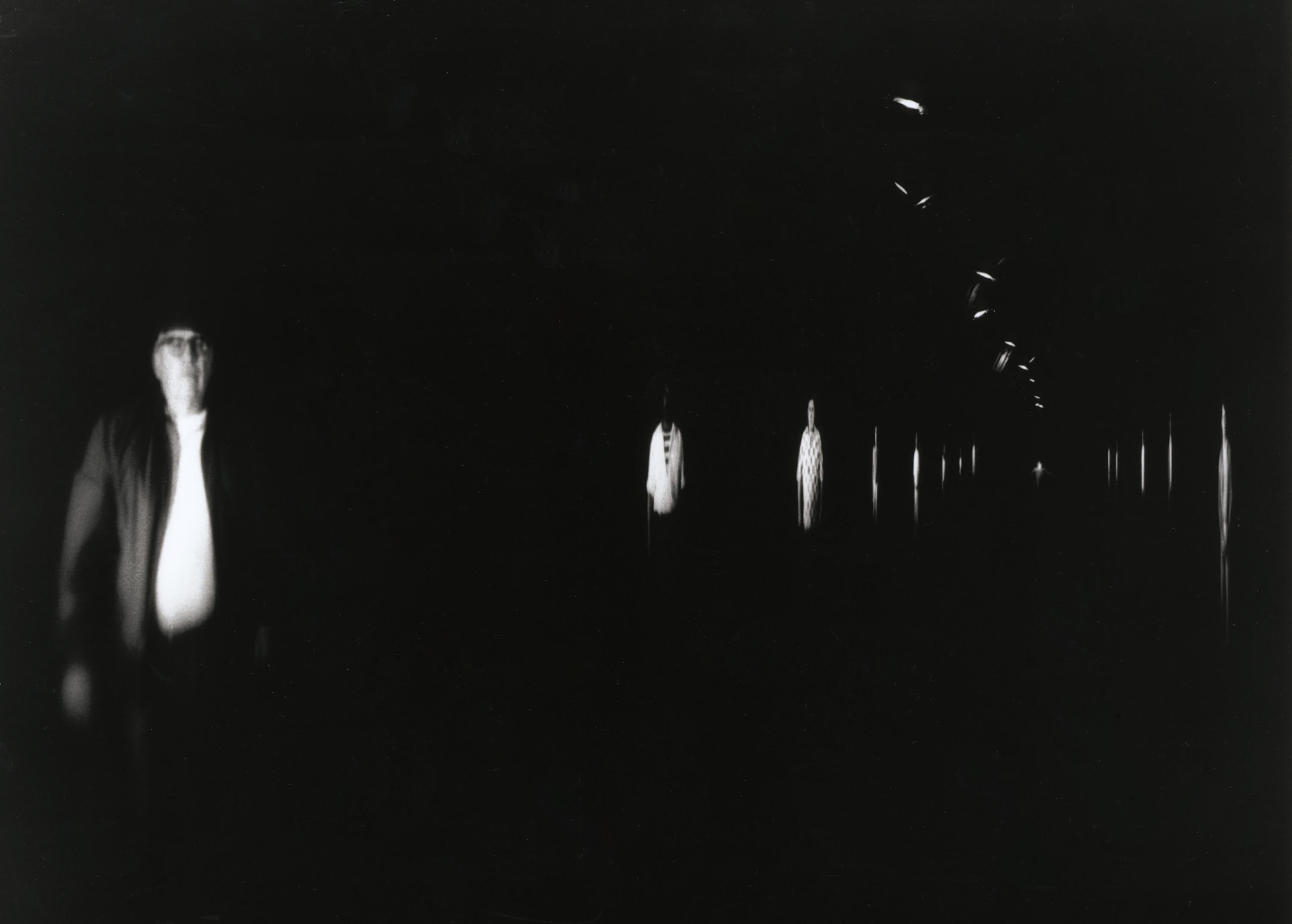 A long, dark corridor stretches out, and multiple images of people are projected in black and white on the walls.