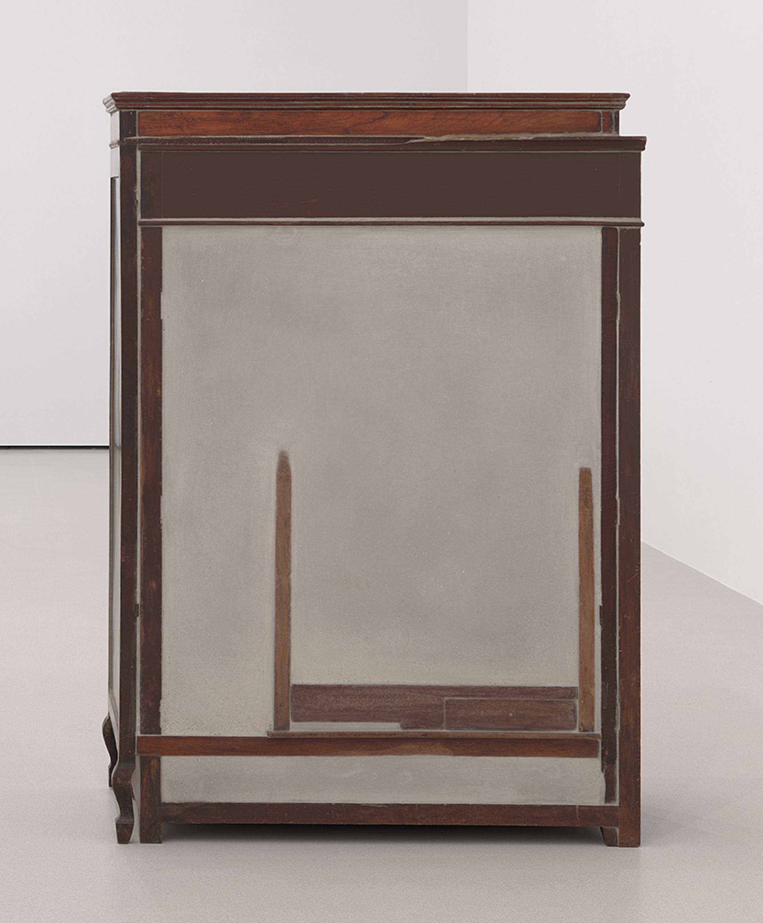 Un armario lleno de hormigón se encuentra en el suelo de la galería. Una mesa está incrustada dentro del hormigón.