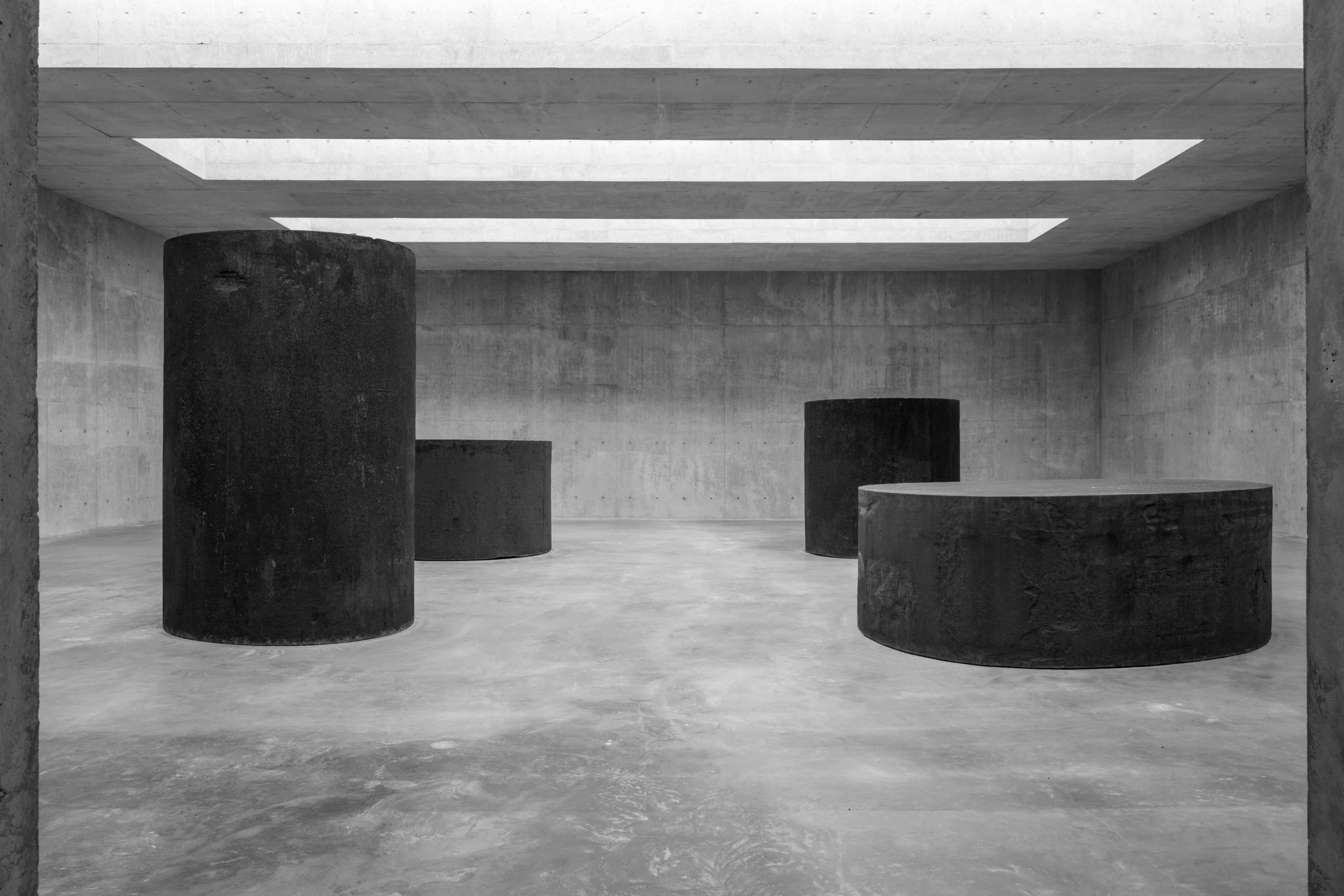 Four cylinders made of steel sit in a large room.