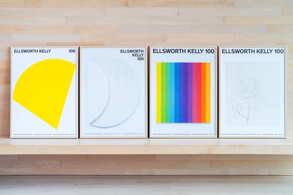 Four framed Ellsworth Kelly posters sit on a bench in the Arrival Hall