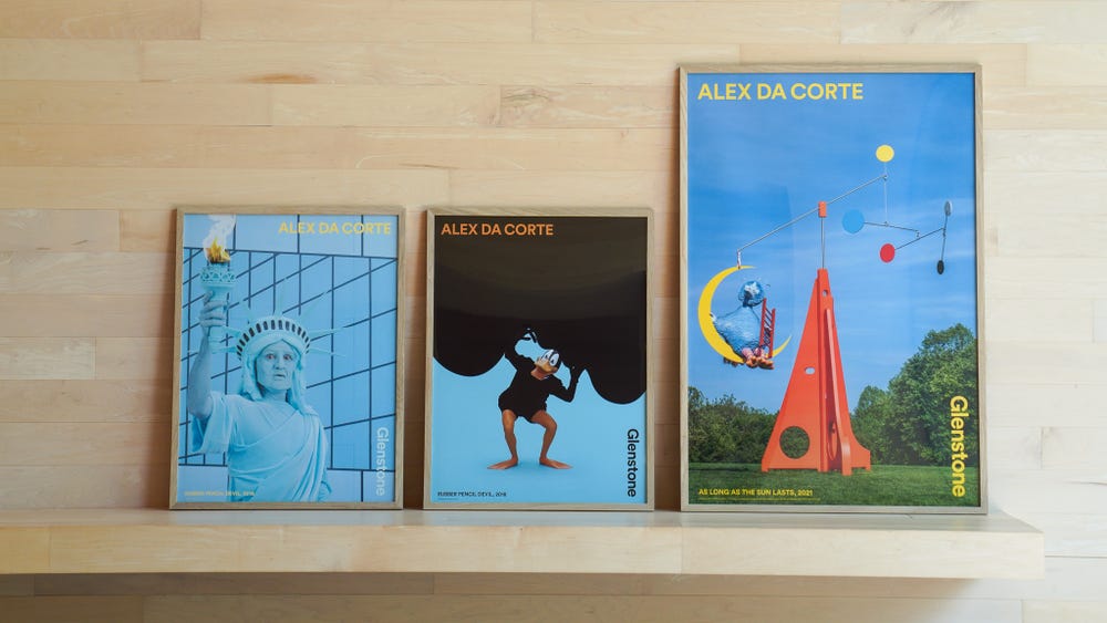 Posters of works by Alex Da Corte sit on a wooden bench.