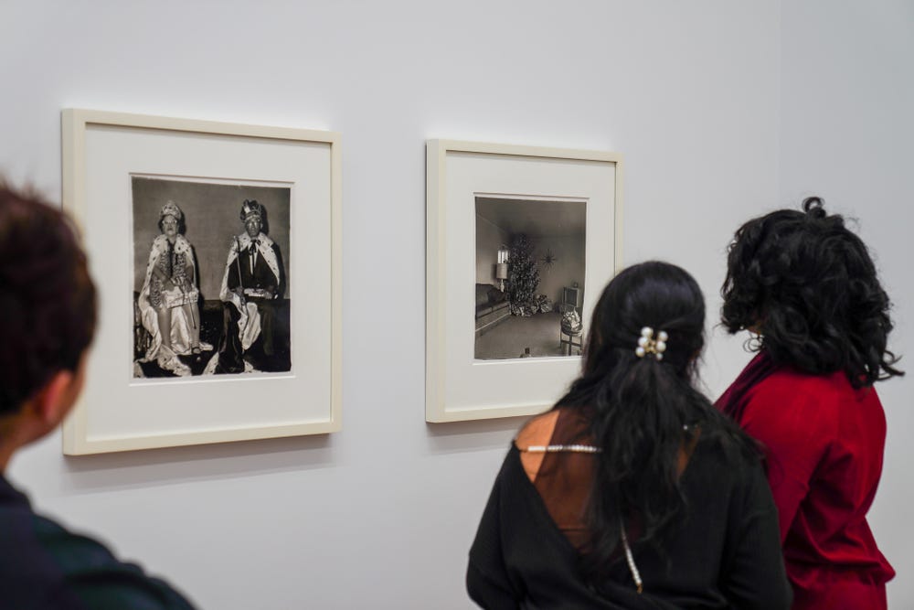 Three students look at two photographs in a gallery