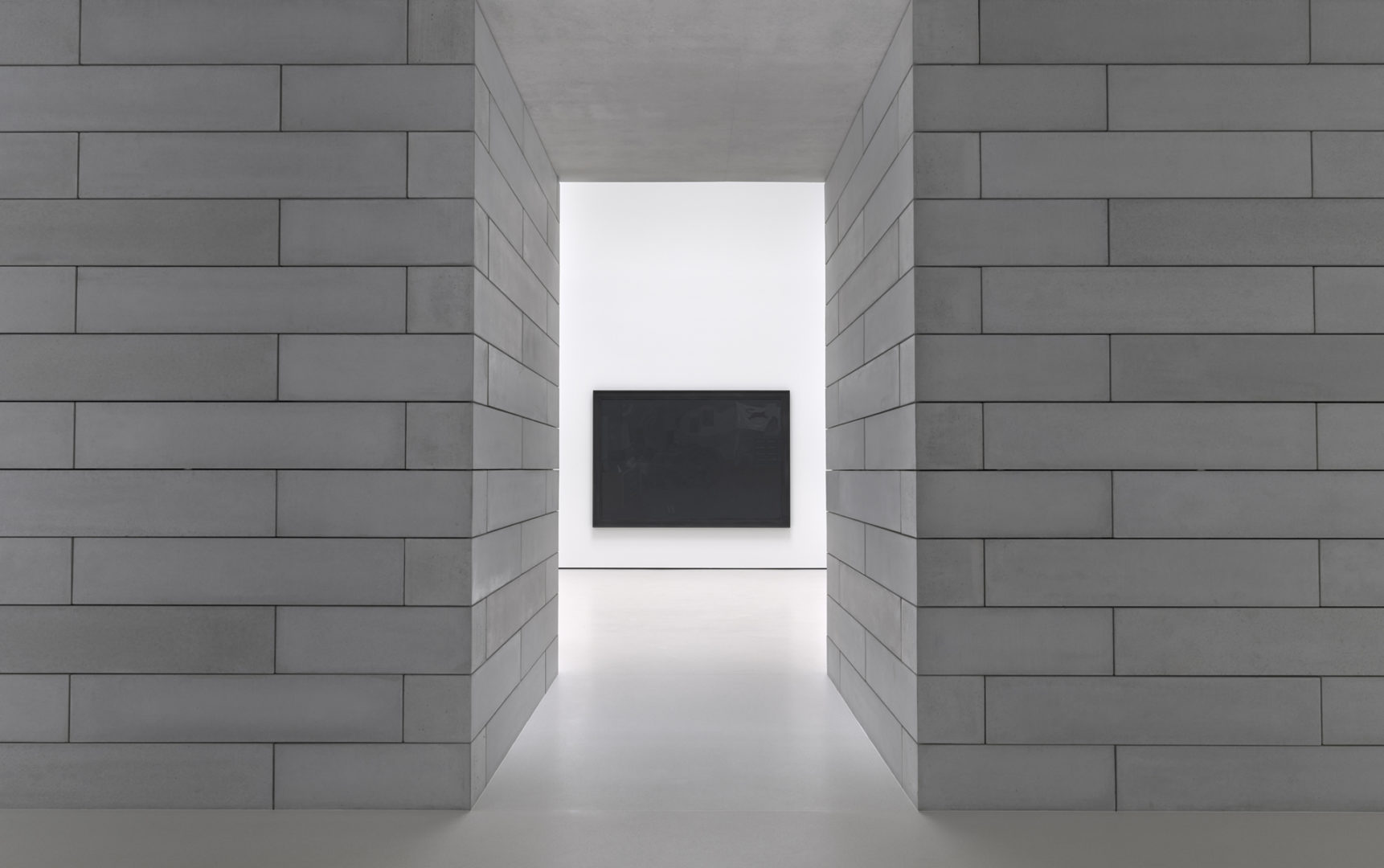 A black painting is centered, visible through a doorway framed by gray concrete blocks.
