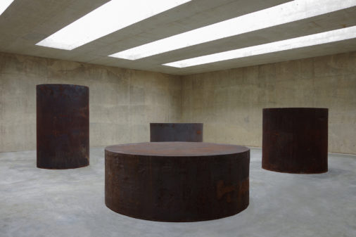 Four large steel cylinders sit in a daylit concrete room.